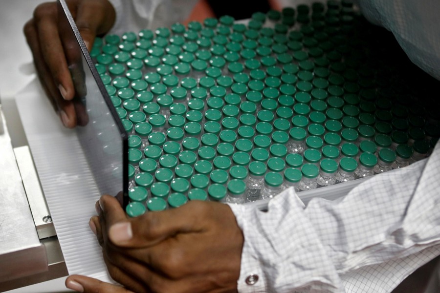 An employee in personal protective equipment (PPE) removes vials of AstraZeneca's COVISHIELD, coronavirus disease (Covid-19) vaccine from a visual inspection machine inside a lab at Serum Institute of India, in Pune, India on November 30, 2020 — Reuters/Files