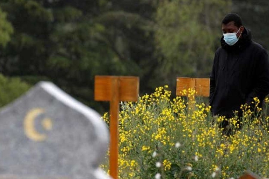 Mamadou Diagouraga, who lost his 71-year-old father Boubou Diagouraga in March 2020 after being infected by the coronavirus disease (COVID-19), stands next to his grave during an interview with Reuters, in the Muslim section of the cemetery in Valenton, near Paris, France, May 6, 2021