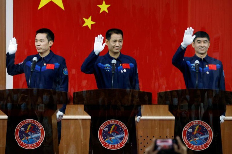 Chinese astronauts Nie Haisheng, Liu Boming, and Tang Hongbo wave as they meet members of the media behind a glass wall before the Shenzhou-12 mission to build China's space station, at Jiuquan Satellite Launch Center near Jiuquan, Gansu province, China on June 16, 2021 — Reuters photo