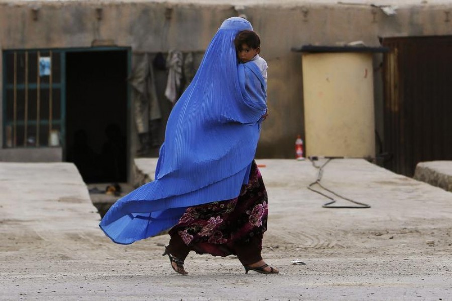 An Afghan woman wearing a burqa holds her child as she walks along a street on the outskirts of Kabul on May 13, 2013 — Reuters/Files