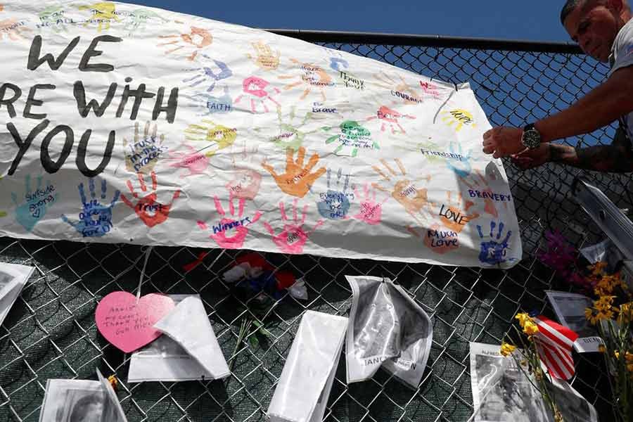 A member of the Miami-Dade Fire Rescue unit placing a sign on a makeshift memorial for the victims of the Surfside's Champlain Towers South condominium collapse in Miami of US on July 8 -Reuters file photo