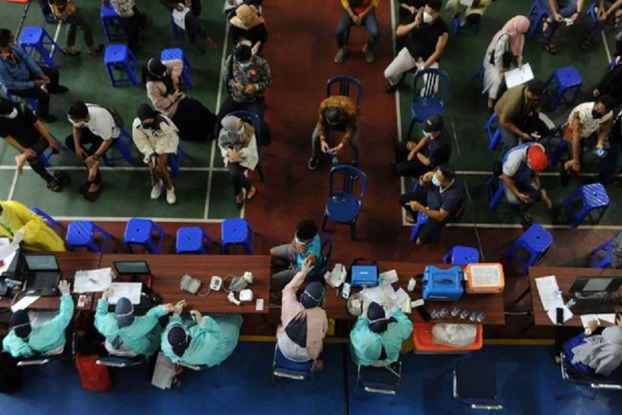 People wearing protective face masks sit before receiving the coronavirus disease (COVID-19) vaccine during the mass vaccination programme for the financial services industry at a school, as cases surge in Palembang, South Sumatra province, Indonesia Jul 13, 2021. REUTERS