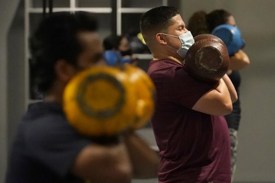 In this Nov 24, 2020, file photo, Juan Avellan, center, and others wear masks while working out in an indoor class at a Hit Fit SF gym amid the coronavirus outbreak in San Francisco – AP Photo