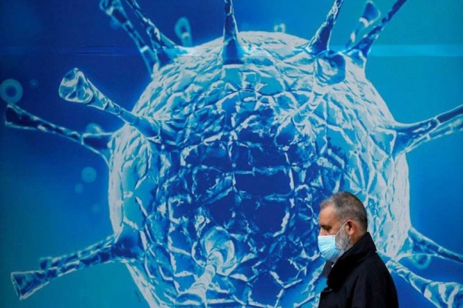 A man wearing a protective face mask walks past an illustration of a virus outside a regional science centre amid the coronavirus disease (COVID-19) outbreak, in Oldham, Britain August 3, 2020. REUTERS/Phil Noble/File Photo