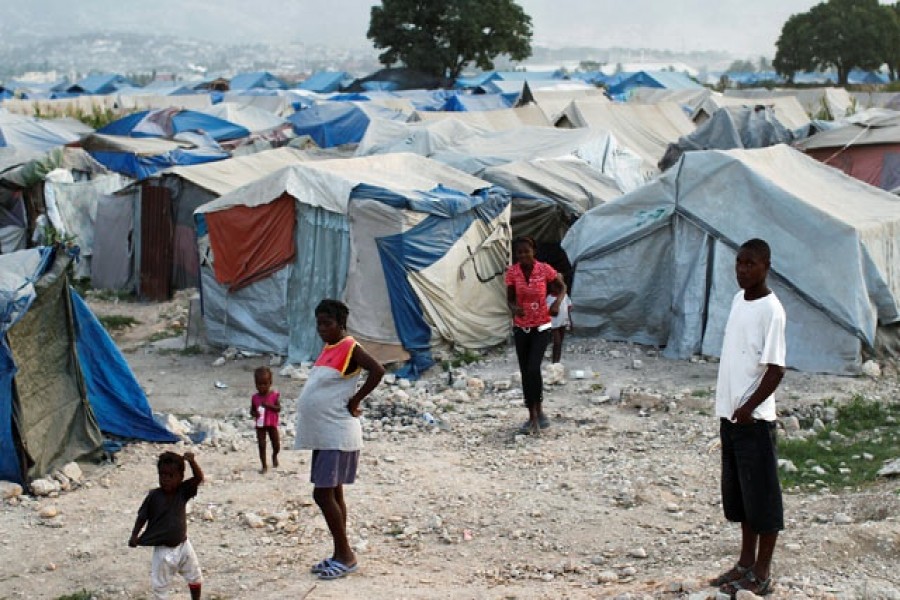 Haitians made homeless in the 2010 earthquake stand outside their tents on the outskirts of Port-au-Prince January 13, 2011. Reuters