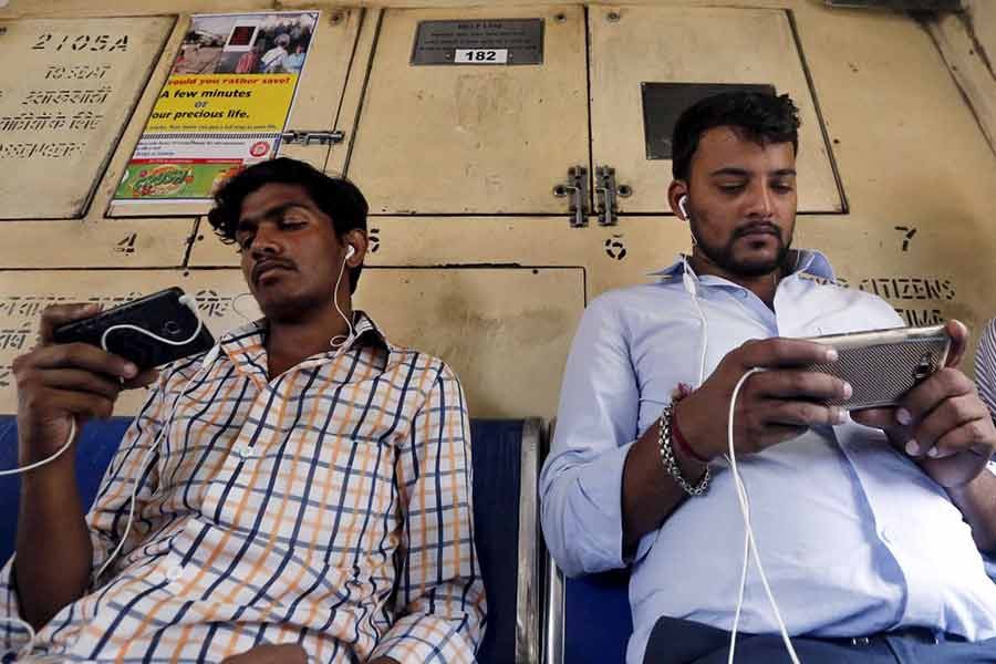 Commuters watching videos on their mobile phones as they travel in a suburban train in Mumbai of India –Reuters file photo