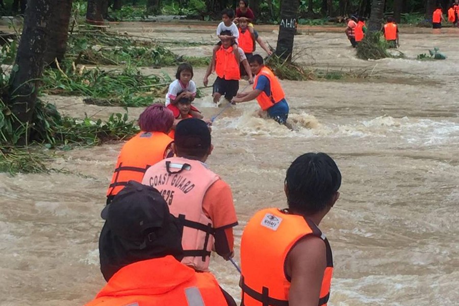 People cross floodwaters caused by tropical cyclone Kompasu during an evacuation assisted by the Philippine Coast Guard (PCG) at Brooke's Point, Palawan, in the Philippines on Ocotober 12, 2021, in this image obtained via social media — Philippine Coast Guard via REUTERS