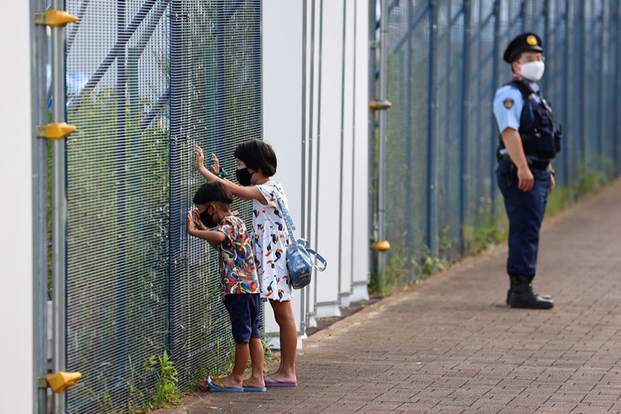 A boy and a girl wearing protective masks look through the fence of Aomi Urban Sports Park, hosting 3x3 basketball tournaments, a day after the official opening of Tokyo 2020 Olympic Games in Tokyo, Japan on July 24, 2021 — Reuters/Files