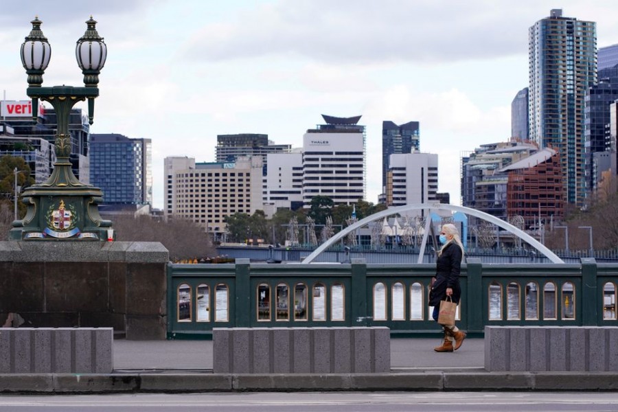 A lone woman, wearing a protective face mask, walks across a city centre bridge as the state of Victoria looks to curb the spread of a coronavirus disease (Covid-19) outbreak in Melbourne, Australia on July 16, 2021 — Reuters/Files