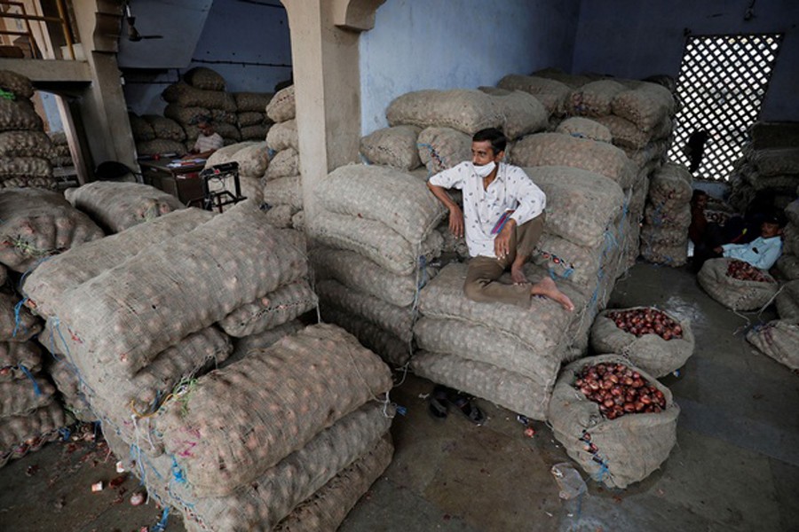 A vendor sits on the sacks of onion as he waits for customers at a vegetable market in Ahmedabad, India, October 11, 2021. Picture taken October 11, 2021. REUTERS/Amit Dave