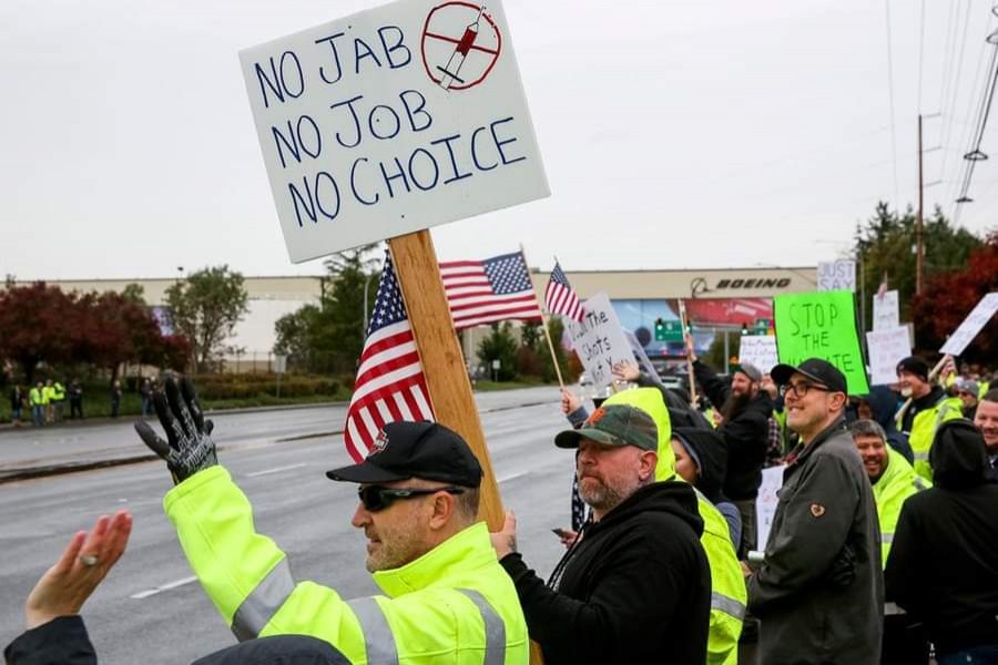 Boeing employees and others line the street with signs and American flags as they protest the company's coronavirus disease (Covid-19) vaccine mandate, outside the Boeing facility in Everett, Washington on October 15, 2021 - Reuters photo