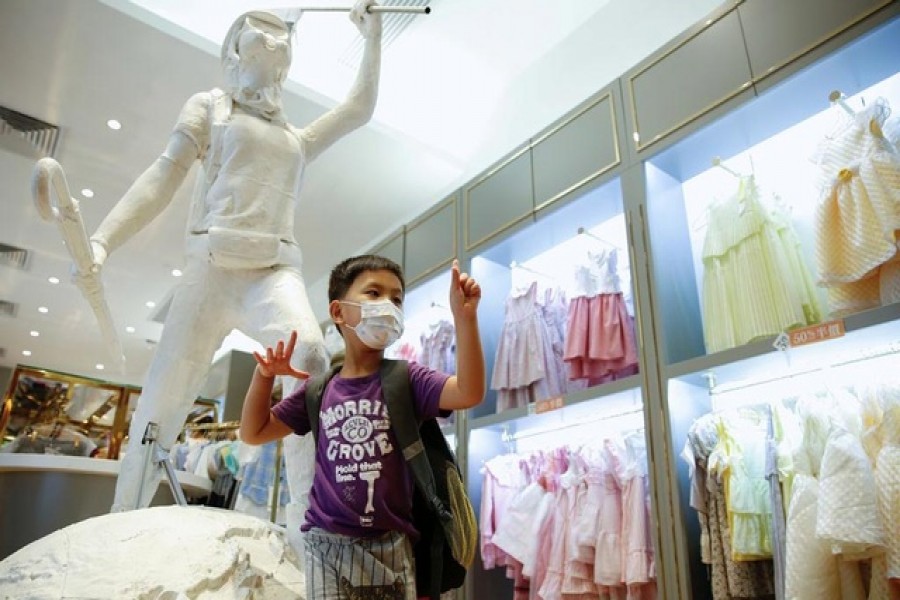 A child poses next to the two-meter-tall "Lady Liberty", a symbolic statue placed by pro-democracy protesters at a Chickeeduck branch in Hong Kong, China June 18, 2020. REUTERS