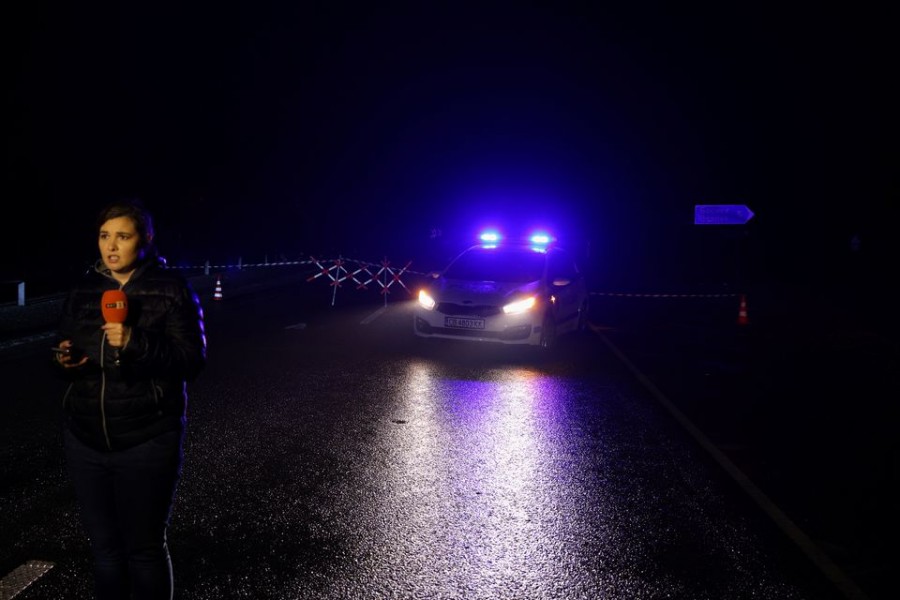 A member of the media stands near a police car, close to the site where at least 45 people were killed when a bus with North Macedonian plates caught fire on a highway, near the village of Bosnek, in Bulgaria, November 23, 2021. REUTERS/Stoyan Nenov