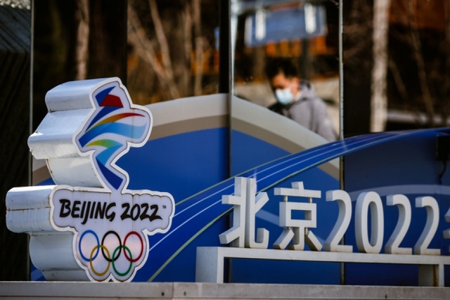 A man is reflected in a mirror as he walks past the logo of the Beijing 2022 Olympics in Beijing, China, November 30, 2021. Picture taken November 30, 2021 REUTERS