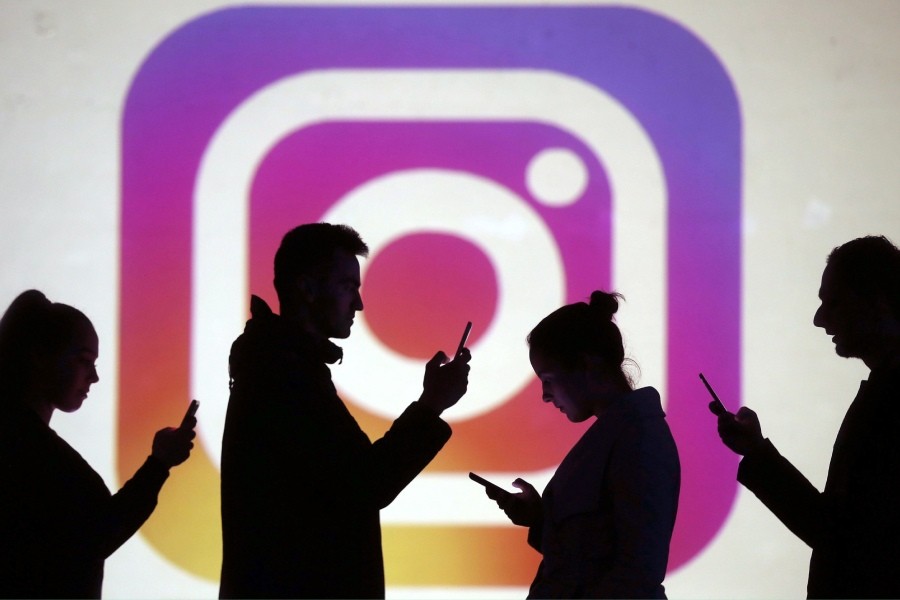 Silhouettes of mobile users are seen next to a screen projection of Instagram logo in this picture illustration -  Reuters