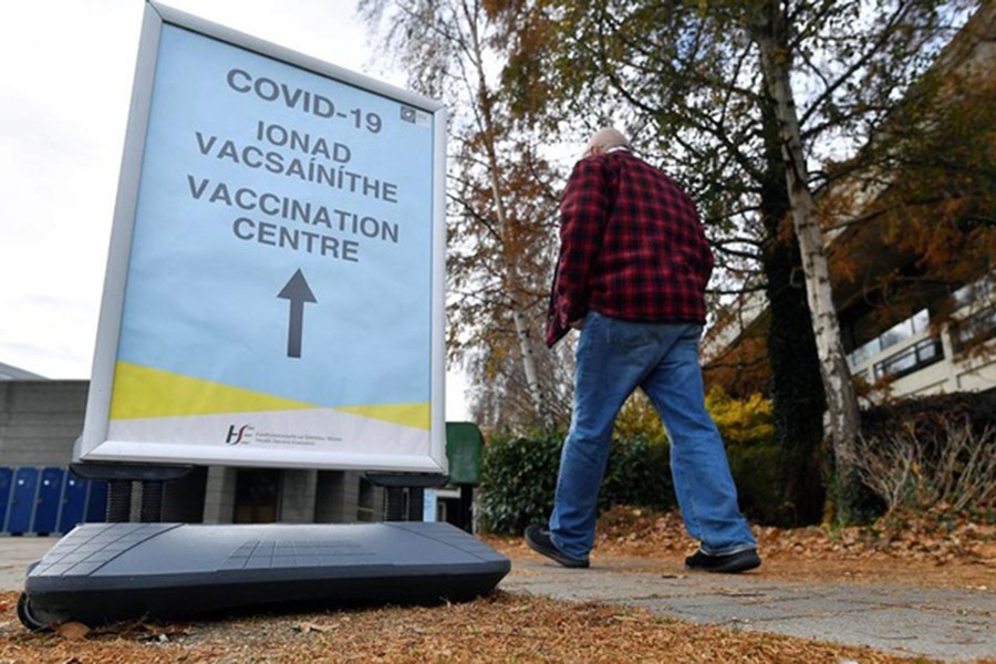 A man walks past a sign for the coronavirus disease (COVID-19) vaccination centre at University College Dublin (UCD) campus clinic for inoculating frontline workers in Dublin, Ireland, November 28, 2021. REUTERS/Clodagh Kilcoyn