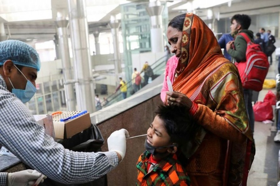 A healthcare worker collects a coronavirus disease (Covid-19) test swab sample from a boy at a bus terminal in New Delhi, India, Dec 6, 2021 – Reuters/Anushree Fadnavis