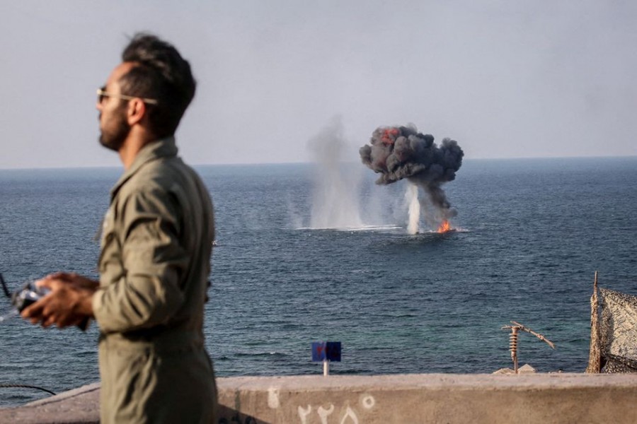 An explosion is seen on the water surface behind a member of the Islamic Revolution Guards Corps (IRGC) during a joint military exercise called the 'Great Prophet 17' in the southwest of Iran, in this picture obtained on December 22, 2021. IRGC/WANA (West Asia News Agency)/Handout via REUTERS