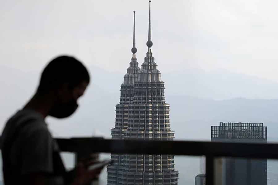 A man wearing a protective mask using his phone as the Petronas Twin Towers are seen in the background, amid the coronavirus disease (COVID-19) pandemic in Kuala Lumpur of Malaysia of April 12 this year -Reuters file photo