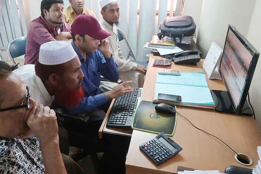 Investors monitoring stock price movements on computer screens at a brokerage house in the capital city — FE/Files