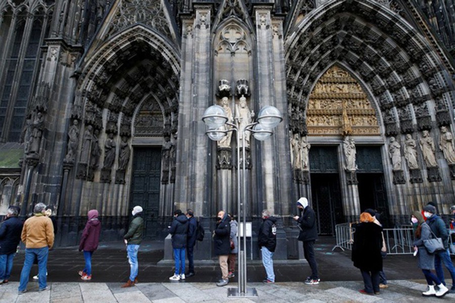 People queue to receive a dose of the Pfizer-BioNTech COVID-19 vaccine during a vaccination event in the Cologne Cathedral on Christmas Eve amid the coronavirus disease (COVID-19) pandemic in Cologne, Germany, Dec 24, 2021. REUTERS/Thilo Schmuelgen