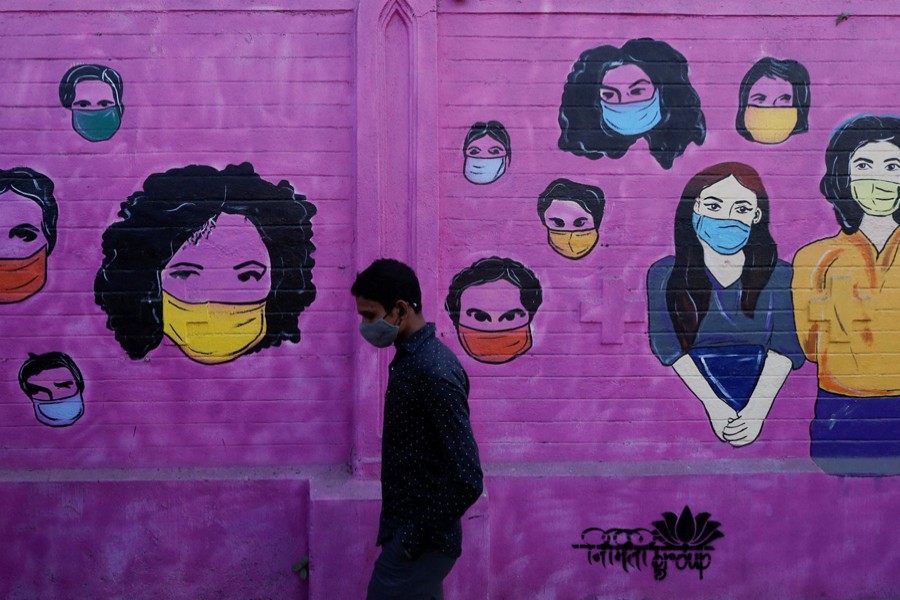 A man wearing a protective face mask walks past a mural on a street, amidst the spread of the coronavirus disease (Covid-19), in Mumbai, India on January 10, 2022 — Reuters photo