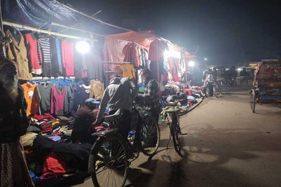 Photo shows an old man buying warm clothes from a roadside makeshift shop in a upazila of Lalmonirhat district — FE Photo