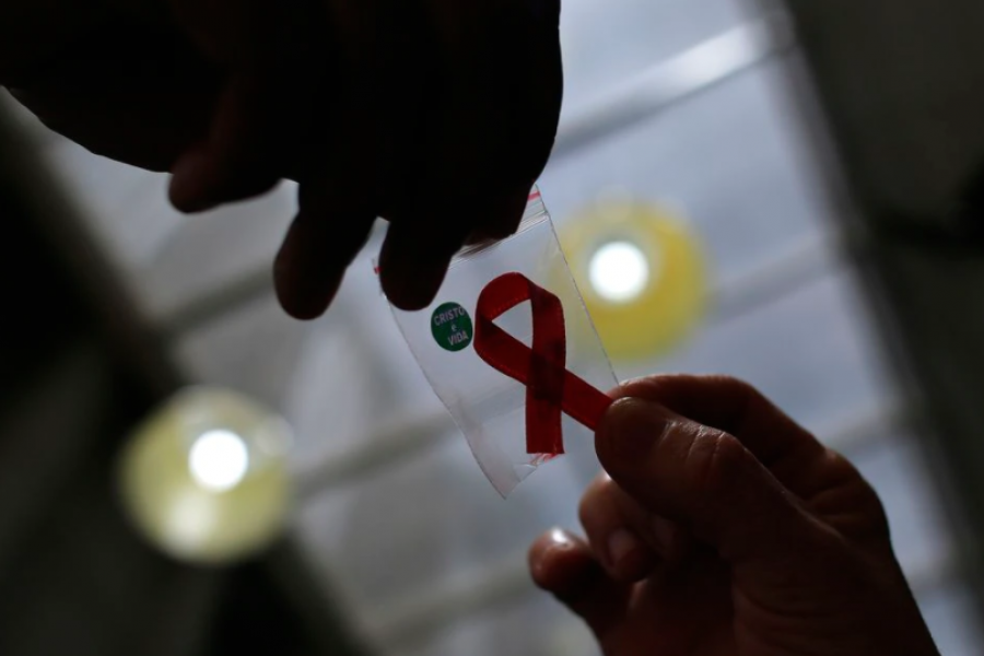 A nurse (L) hands out a red ribbon to a woman, to mark World Aids Day, at the entrance of Emilio Ribas Hospital, in Sao Paulo December 1, 2014. REUTERS/Nacho Doce