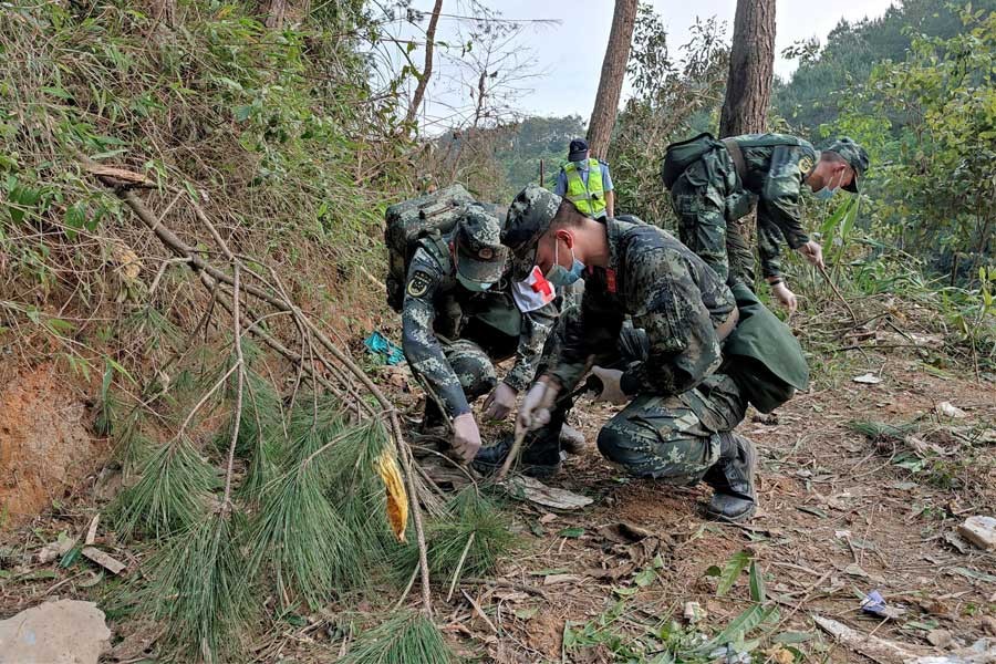 Paramilitary police officers work at the site where a China Eastern Airlines Boeing 737-800 plane flying from Kunming to Guangzhou crashed, in Wuzhou, Guangxi Zhuang Autonomous Region, China March 21, 2022. Picture taken March 21, 2022. China Daily via REUTERS