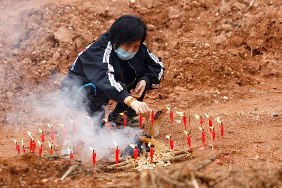 A woman surnamed Liang, 60, takes part in a Buddhist ceremony in honor of the victims in a field close to the entrance of Simen village, near the site where a China Eastern Airlines Boeing 737-800 plane flying from Kunming to Guangzhou crashed, in Wuzhou, Guangxi Zhuang Autonomous Region, China March 22, 2022. REUTERS/Carlos Garcia Rawlins TPX IMAGES OF THE DAY