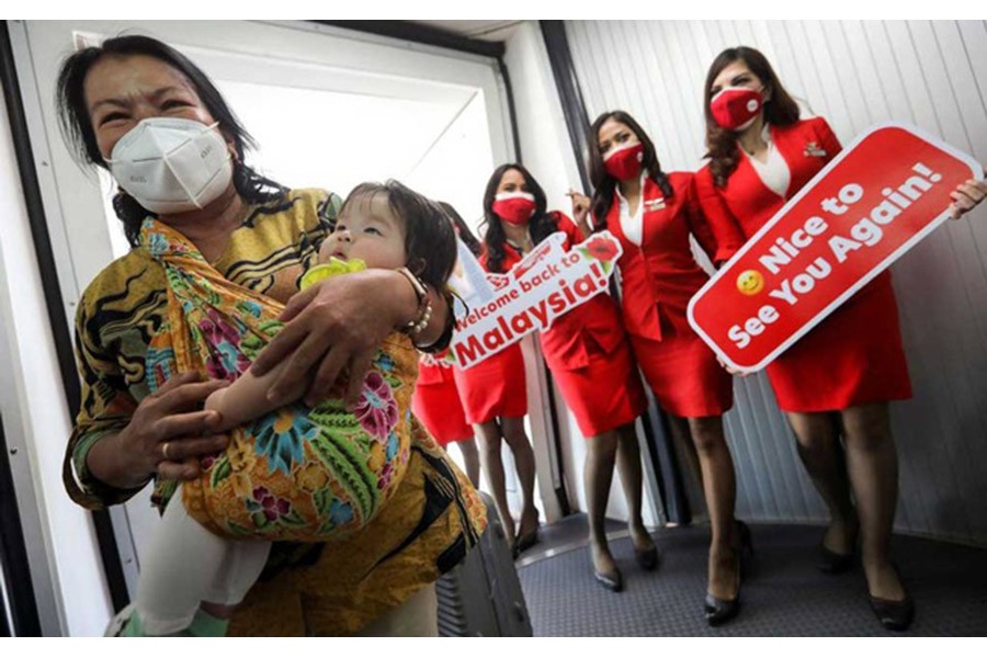 Stewardesses welcome a woman and toddler, as they disembark from an aeroplane from Jakarta, Indonesia at Kuala Lumpur International Airport 2 (KLIA2), as the country reopens its borders fully to allow entry without quarantine for visitors vaccinated against coronavirus disease (COVID-19) in Sepang, Selangor, Malaysia, Apr 1, 2022. REUTERS/Hasnoor Hussain