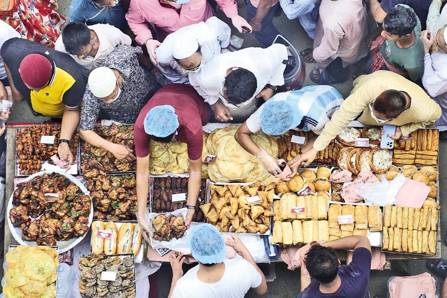 People buy traditional Iftar items from a makeshift shop at Chawkbazar in Old Dhaka on Sunday - the first day of the holy Ramadan. The popular Iftar hub reopened on the day after remaining closed for the last two years due to the pandemic — Photo by KAZ Sumon