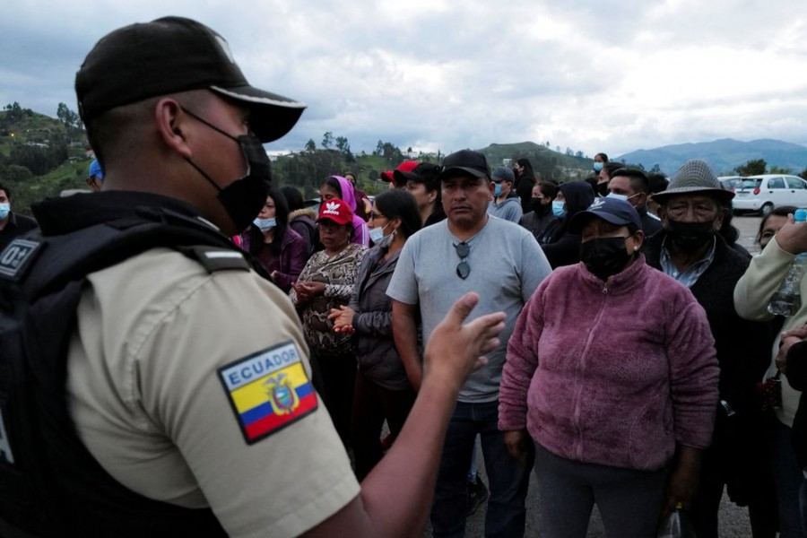 A police officer speaks with relatives of inmates at a police checkpoint as they wait for news of their loved ones after a riot broke out at the El Turi prison where several inmates were killed or injured, in Cuenca, Ecuador April 3, 2022. REUTERS/Fabiola Cedillo