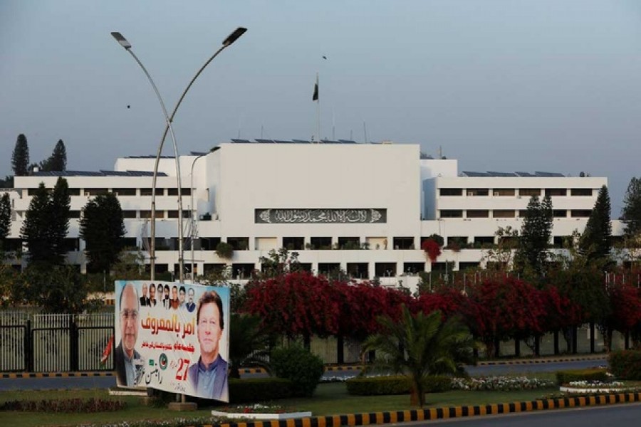 A campaign poster featuring Pakistani Prime Minister Imran Khan is seen with the parliament building in the background, in Islamabad, Pakistan Apr 2, 2022 — Reuters/Files