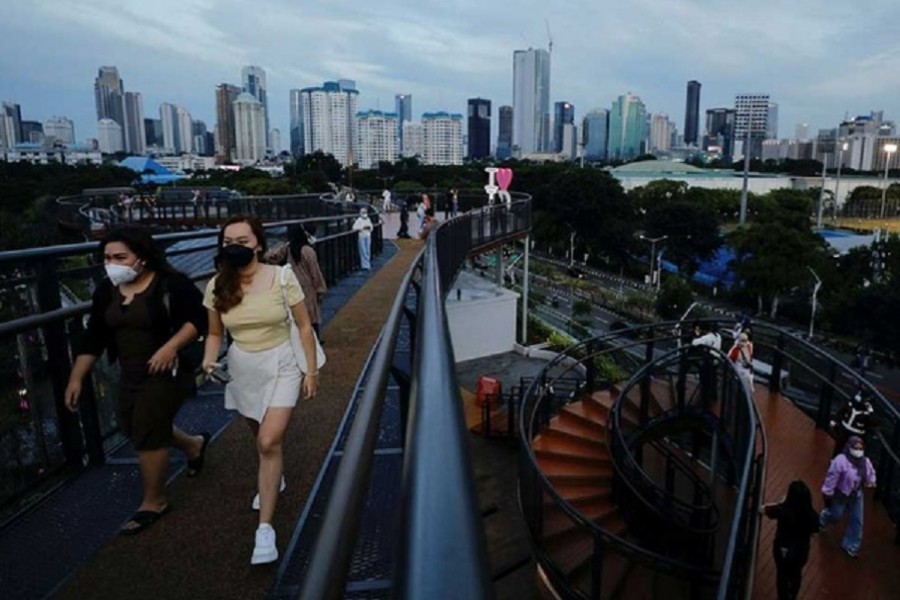 People wearing protective face masks enjoy a stroll along a skywalk bridge as the omicron coronavirus variant continues to spread, in Jakarta, Indonesia, Feb 7, 2022. REUTERS/Willy Kurniawan