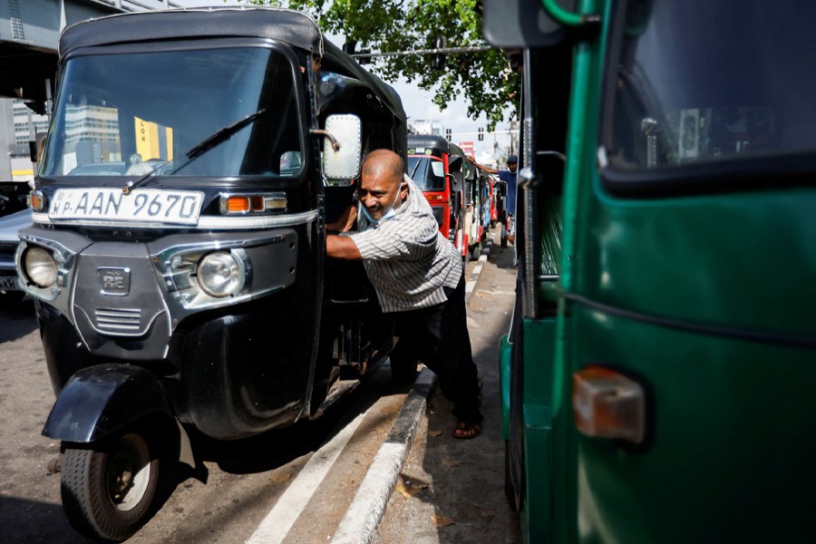 A Piyasiri, an auto driver, pushes his auto as he runs out of fuel while waiting in a queue for two hours, amid the country's economic crisis, in Colombo, Sri Lanka on April 18, 2022 — Reuters photo