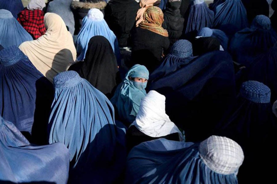 A girl sits in front of a bakery in the crowd with Afghan women waiting to receive bread in Kabul, Afghanistan, January 31, 2022. REUTERS/Ali Khara