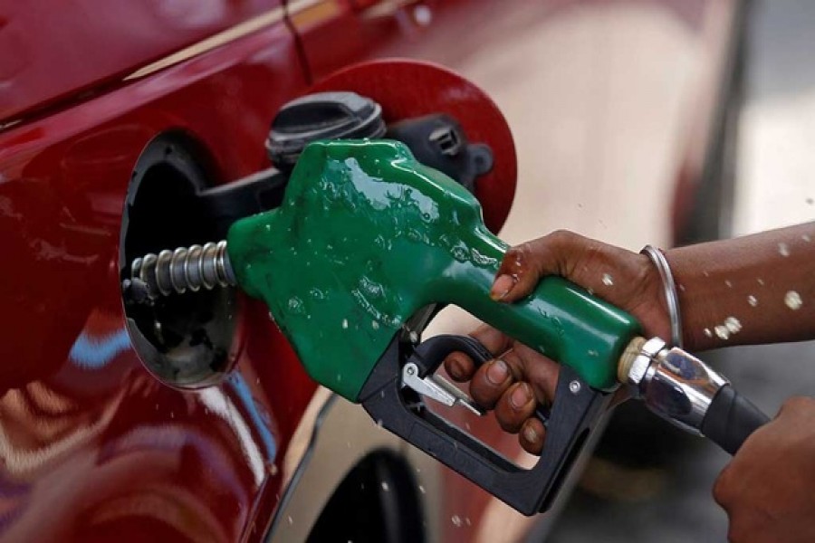 A worker holds a nozzle to pump petrol into a vehicle at a fuel station in Mumbai, India, May 21, 2018. REUTERS/Francis Mascarenhas