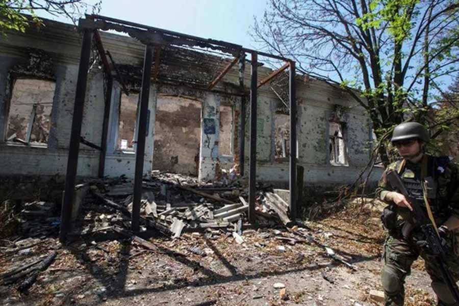 A police officer checks an area during an evacuation of local residents between shelling in the village of Novomykhailivka, Donetsk region, Ukraine, May 29, 2022. Reuters