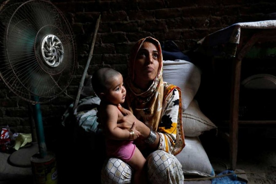 Razia, 25, and her six-month-old daughter Tamanna, sit in front of a fan to cool off during a heatwave, in Jacobabad, Pakistan, May 15, 2022. Reuters