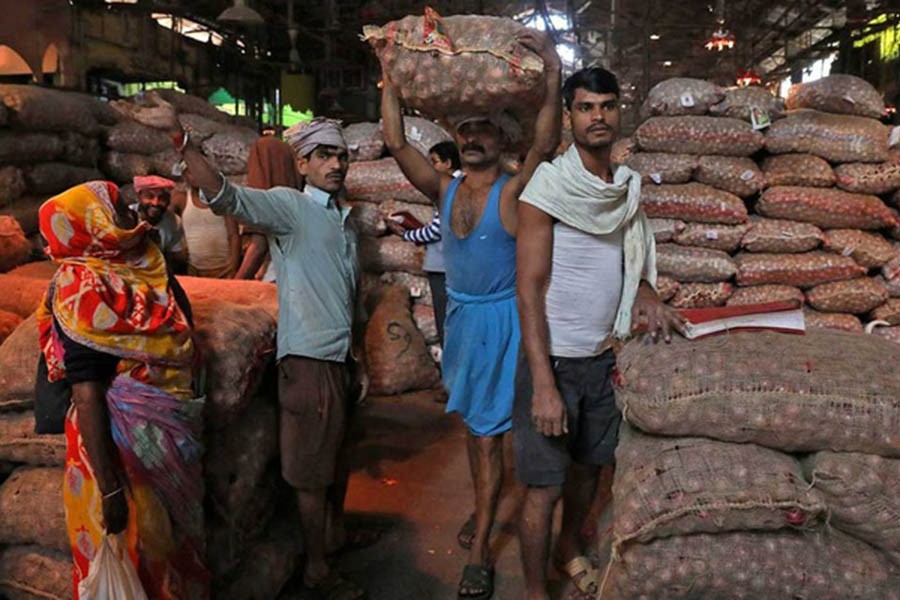 A labourer carries a sack of onions at a wholesale market in Kolkata, India, December 14, 2021. REUTERS