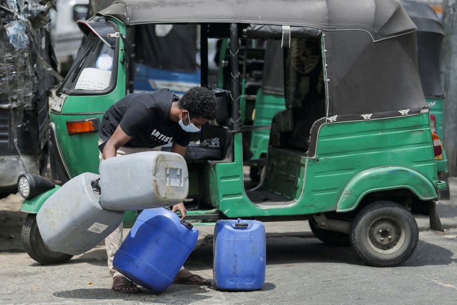 A boy tires to hold cans together as he rushes into a line to buy diesel at a Ceylon Petroleum Corporation fuel station in Colombo, Sri Lanka March 2, 2022. REUTERS/Dinuka Liyanawatte