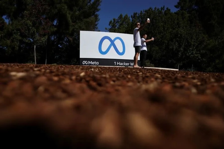 Men take selfies in front of a sign of Meta, the new name for the company formerly known as Facebook, at its headquarters in Menlo Park, California, US Oct 28, 2021. Reuters