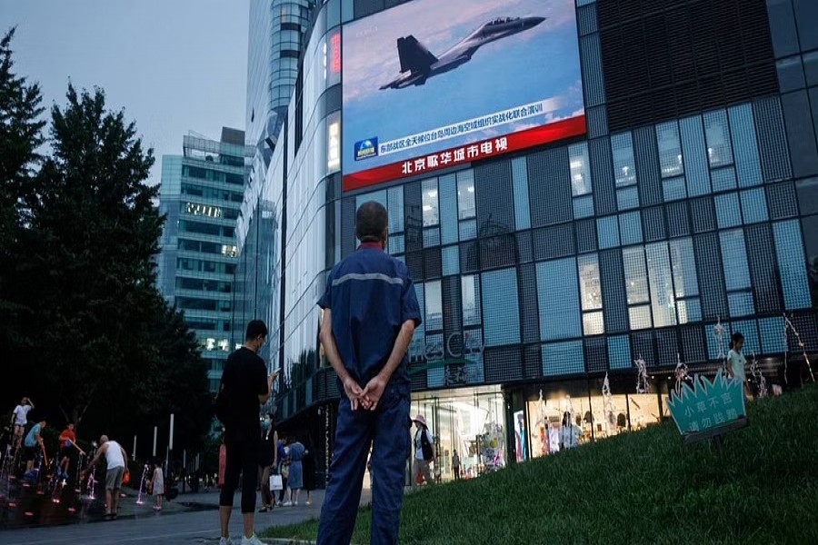 A man watches a CCTV news broadcast, showing a fighter jet during joint military operations near Taiwan by the Chinese People's Liberation Army's (PLA) Eastern Theatre Command, at a shopping centre in Beijing, China, August 3, 2022. REUTERS