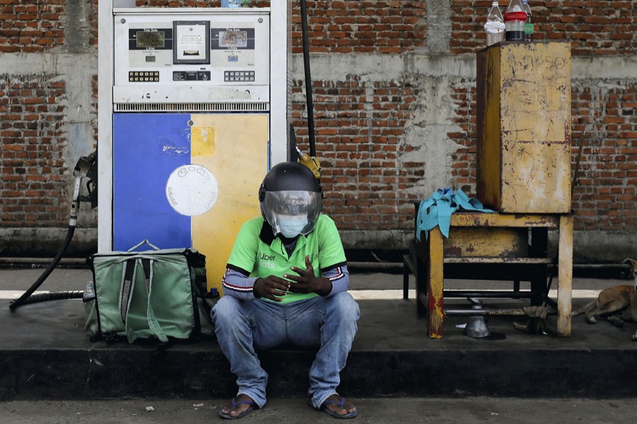 An Uber driver waits at a Ceylon Petroleum Corporation fuel station to buy fuel after his bike ran out of petrol on the road, in Colombo, Sri Lanka on March 22, 2022 — Reuters/Files