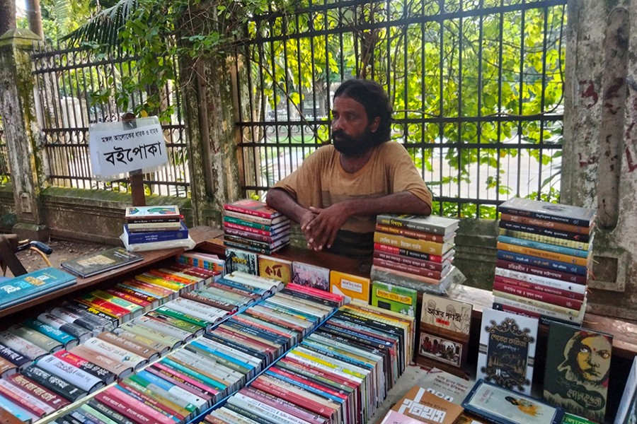ভ্যানে বইয়ের পসরা সাজিয়ে আইএমএলের পাশে দাঁড়ানো মধু মণ্ডল। ছবি: লেখক