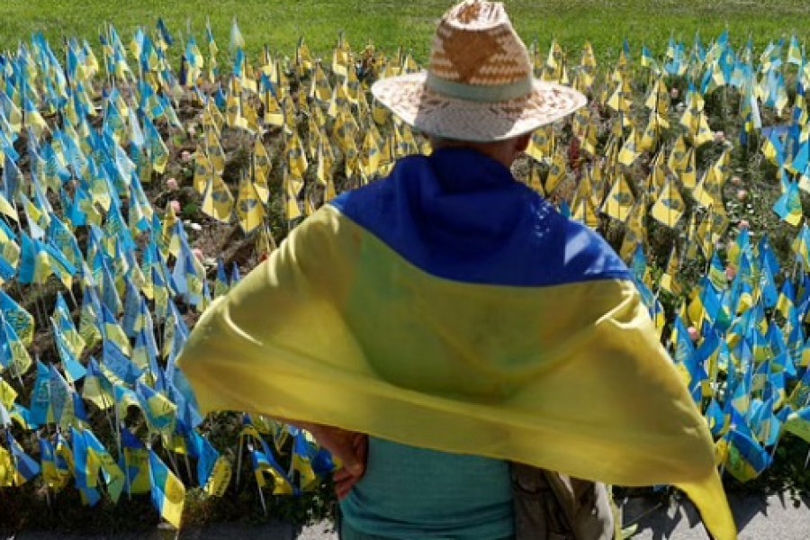 A man stands next to Ukrainian flags with names of service members, who are in Russian captivity, as Russia's attack on Ukraine continues, at the Independence square in Kyiv, Ukraine Aug 24, 2022. REUTERS