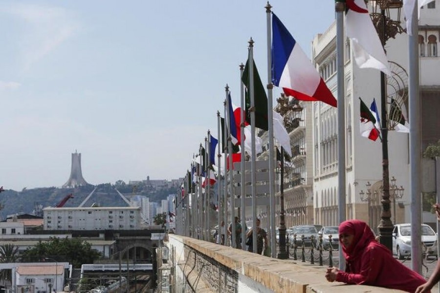 A woman stands near Algerian and French flags ahead of the arrival of French President Emmanuel Macron in Algiers, Algeria August 25, 2022. REUTERS/Ramzi Boudina