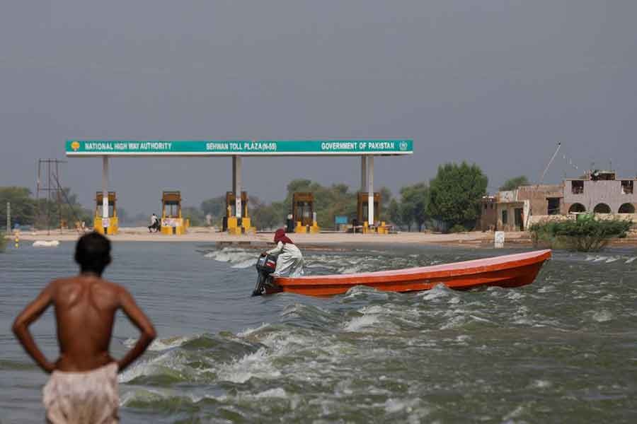 A man riding a boat past toll plaza amid flood water on main Indus highway, following rains and floods during the monsoon season in Sehwan, in Pakistan on Thursday -Reuters file photo