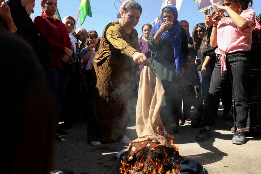 Women burn headscarves during a protest over the death of 22-year-old Kurdish woman Mahsa Amini in Iran, in the Kurdish-controlled city of Qamishli, northeastern Syria September 26, 2022. REUTERS/Orhan Qereman/File Photo